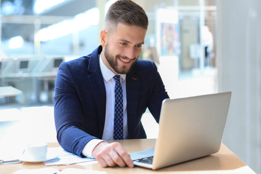 Smiling man sitting in office and using his laptop.